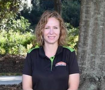 Female employee standing in front of tree