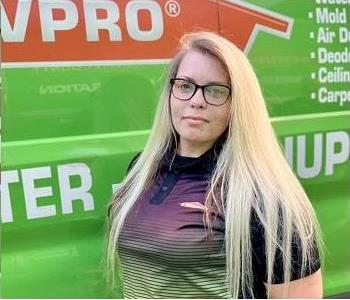 Female employee smiling in front of SERVPRO vehicle