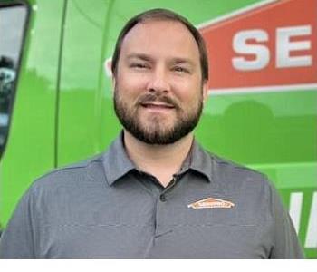 Male employee smiling in front of Servpro Vehicle