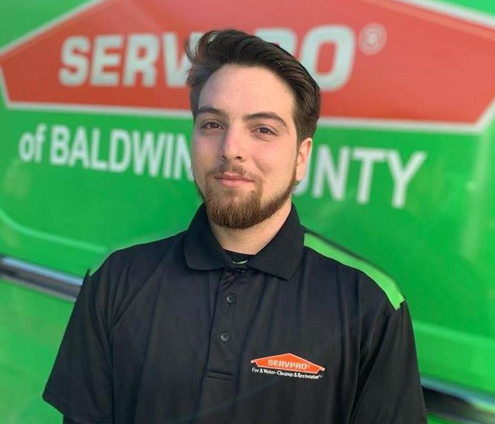 Male employee standing in front of Servpro truck